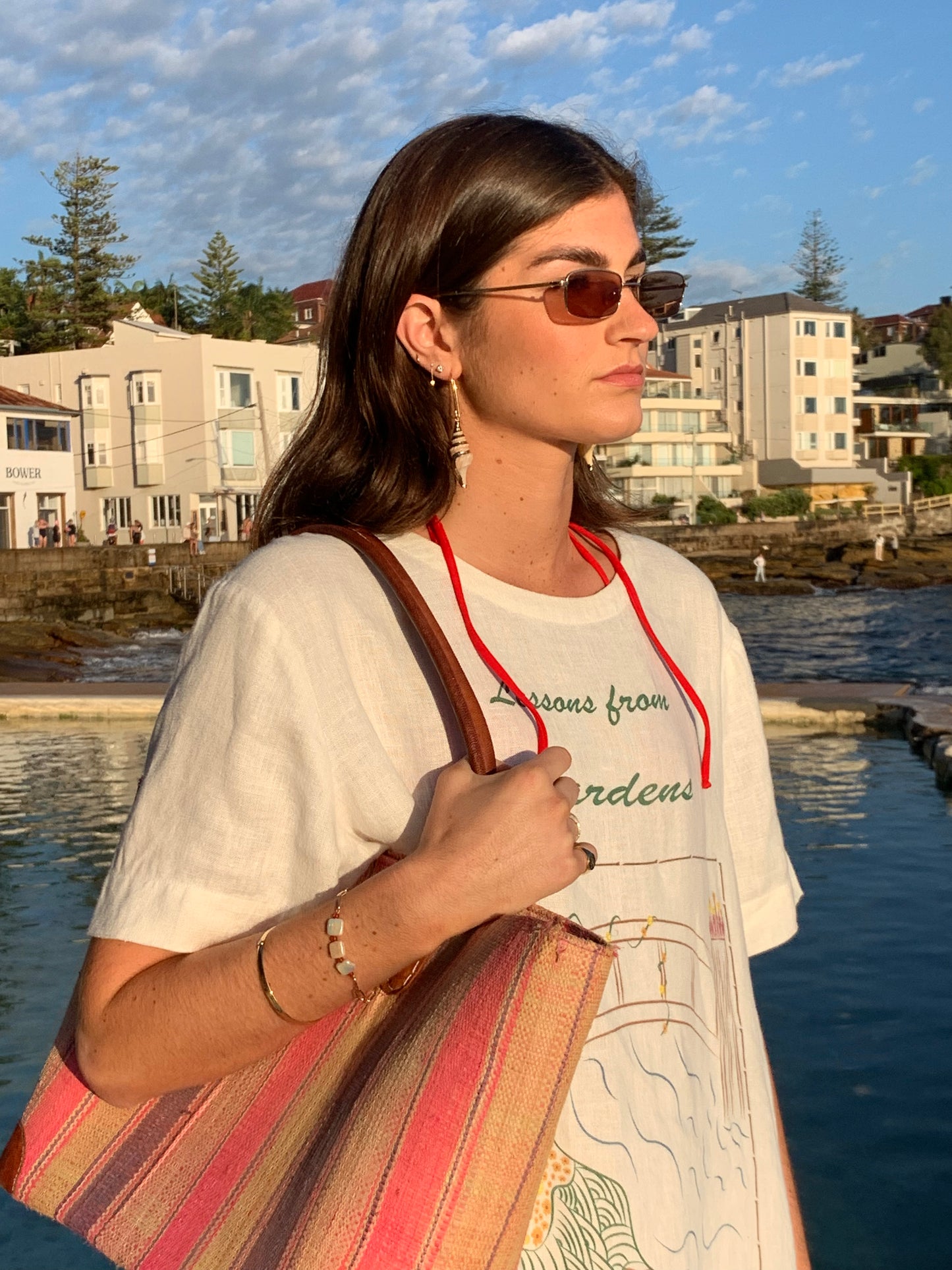 Model wearing Edith Barbarella Sea Salt shell earrings standing next to a pool